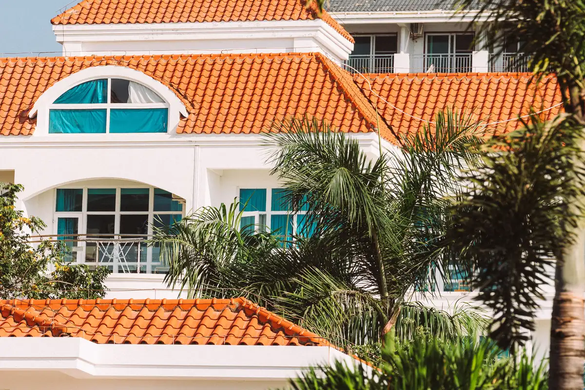 White stucco home with clean orange barrel-tile roofs and palm trees